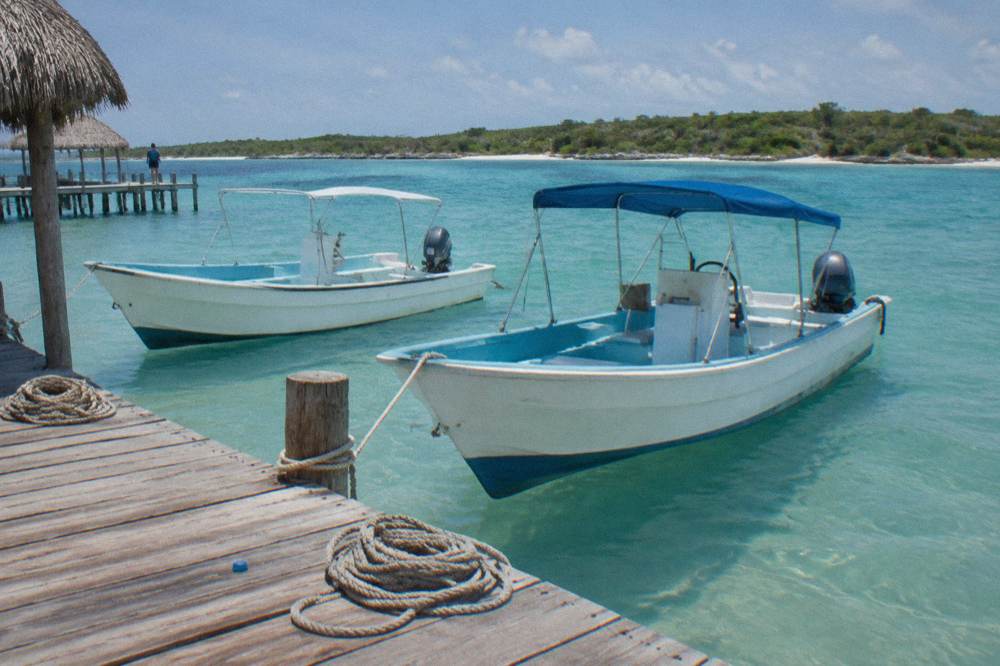 Small dock with moored speedboats in calm turquoise water beside a low shoreline
