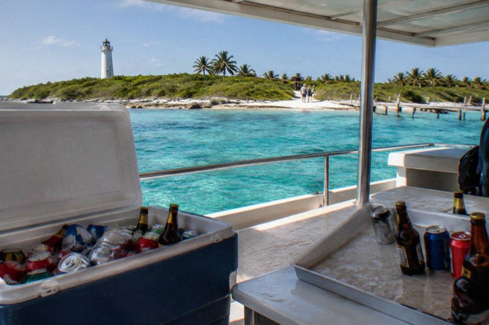 Cooler with cold drinks and a tray of beers under a boat canopy on clear water