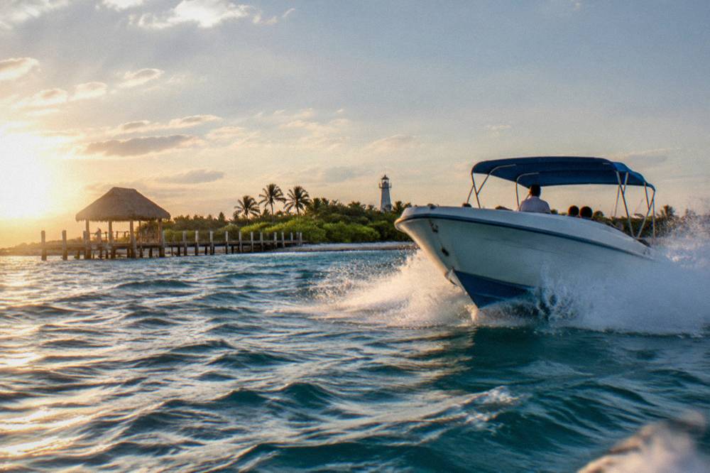 A speedboat cutting through open blue water with spray at the bow