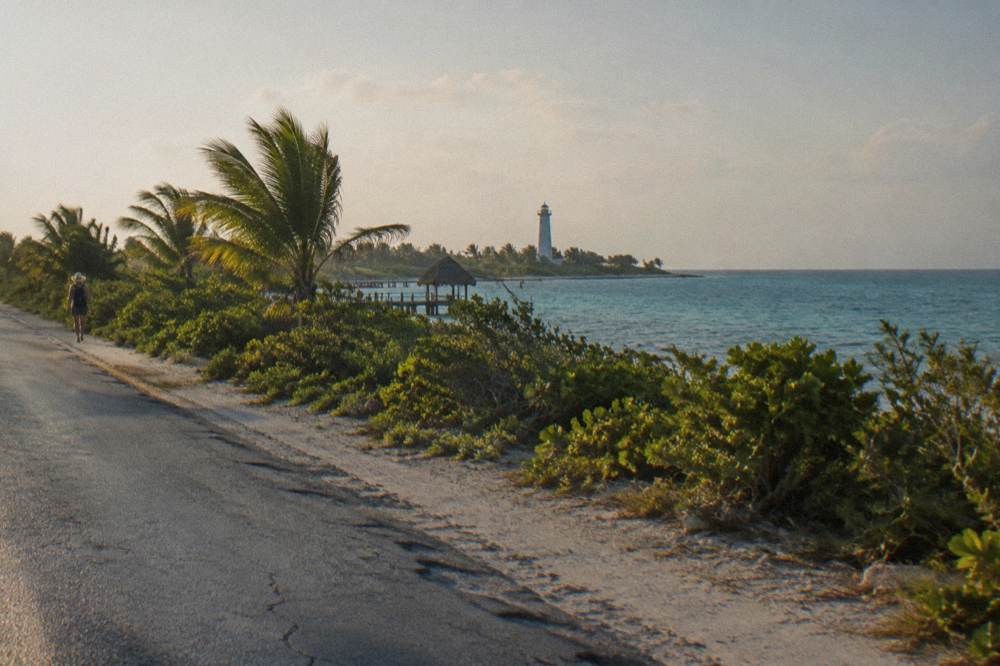 A coastal highway running north toward Cancun with calm sea on one side