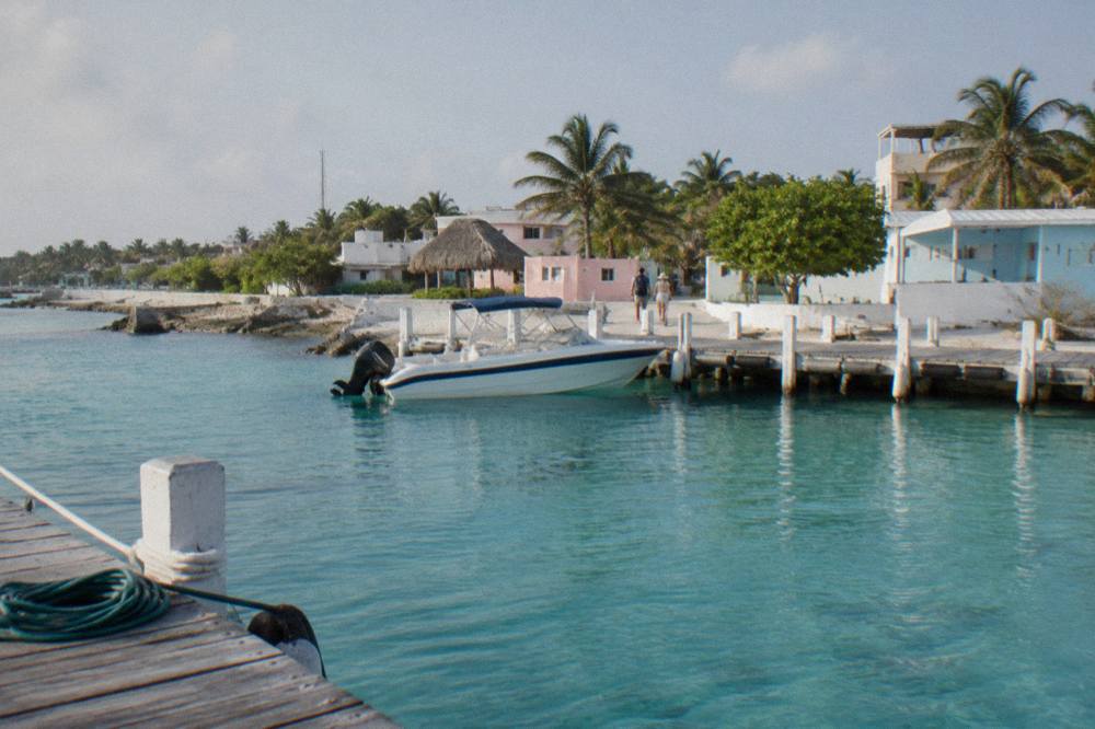 A small white dock on Isla Mujeres with a speedboat tied up and calm turquoise water