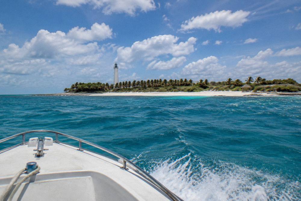A speedboat cutting across open blue water with spray at the bow