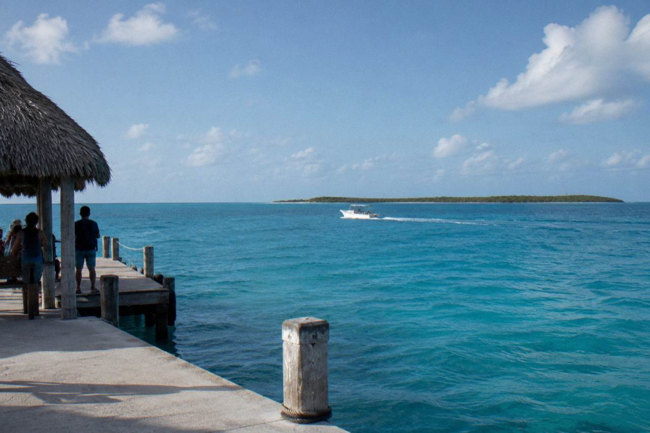 Open Caribbean water between Isla Mujeres and a low green island on the horizon
