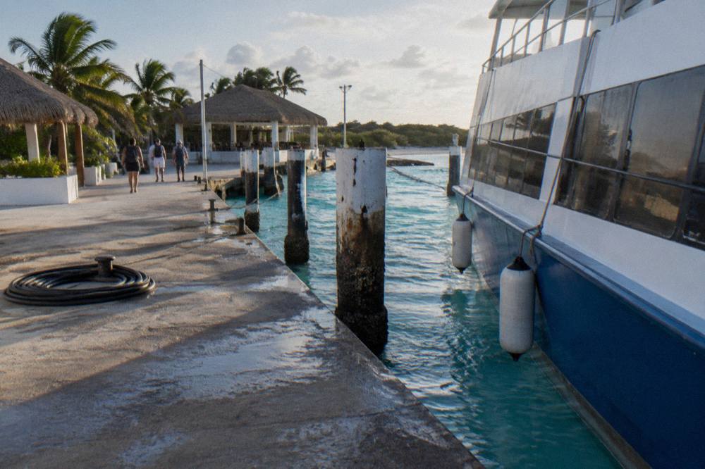 A ferry terminal pier with a moored passenger vessel and calm turquoise water on either side