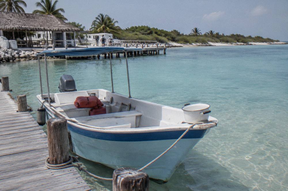 Small tour boat tied at a Caribbean marina dock on a calm morning with clear water