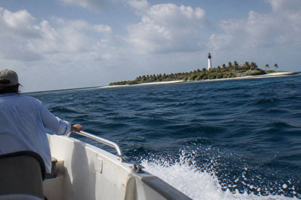 Open speedboat crossing open blue water under a partly cloudy sky