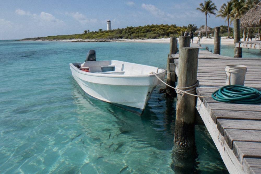 Speedboat moored at a wooden pier beside clear shallow Caribbean water