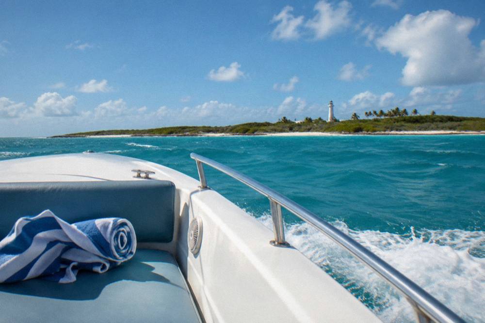 Open speedboat crossing calm turquoise Caribbean water toward a low green island