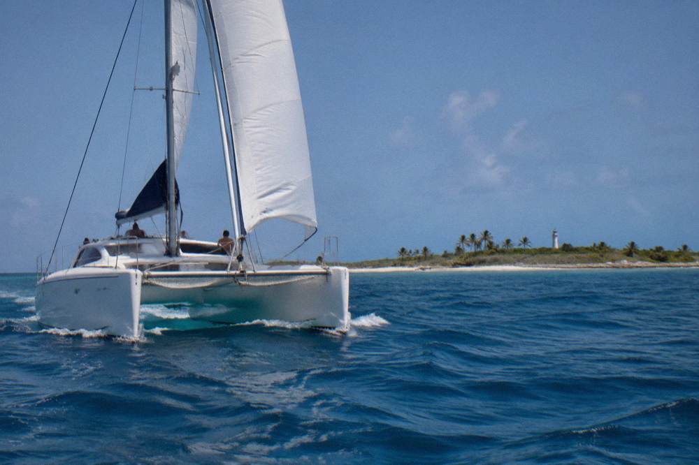 A sailing catamaran with a mast and net trampoline cruising on open blue water