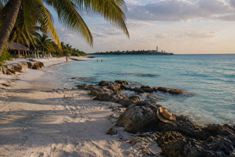 White sand beach and shallow turquoise water along a low rocky point on an island