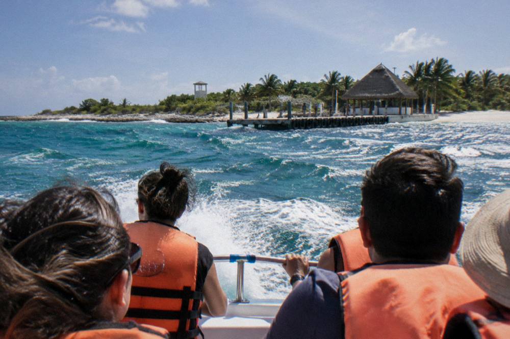 Passengers in life vests riding a small open speedboat across open sea