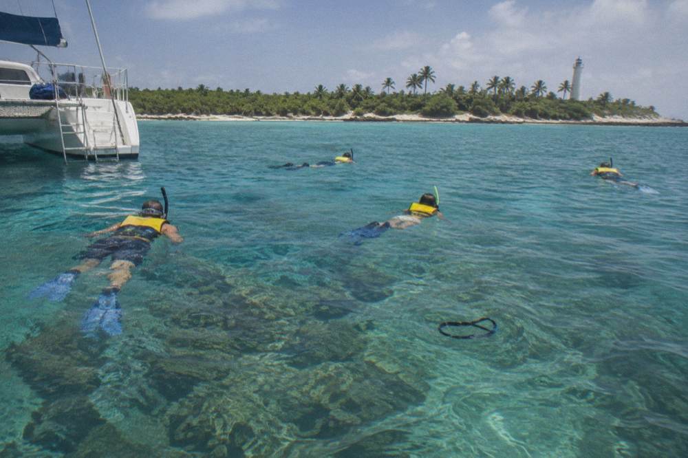 Snorkelers floating above a shallow coral reef in clear turquoise water