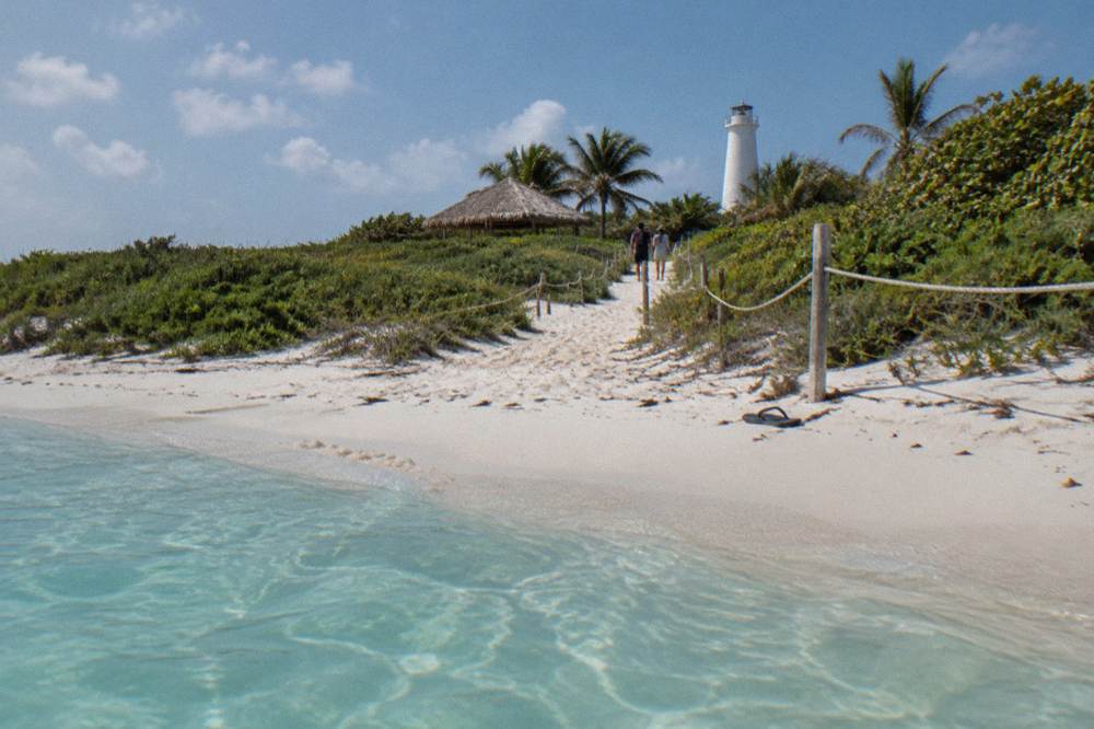 Beach with calm shallow turquoise water and a roped sandy path leading inland