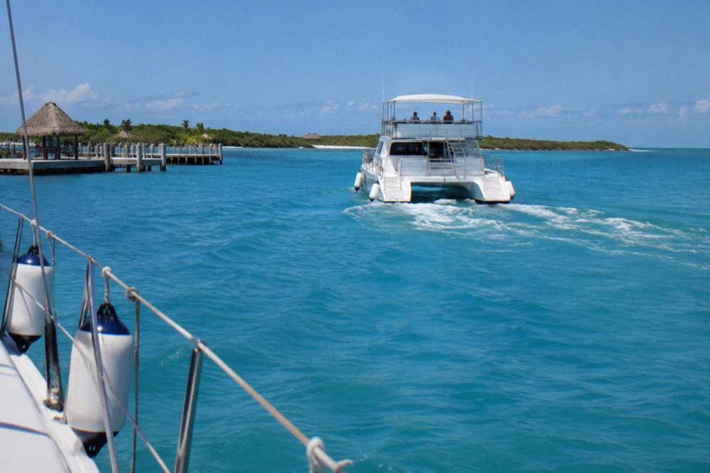 Passenger catamaran underway on open turquoise water toward a distant island