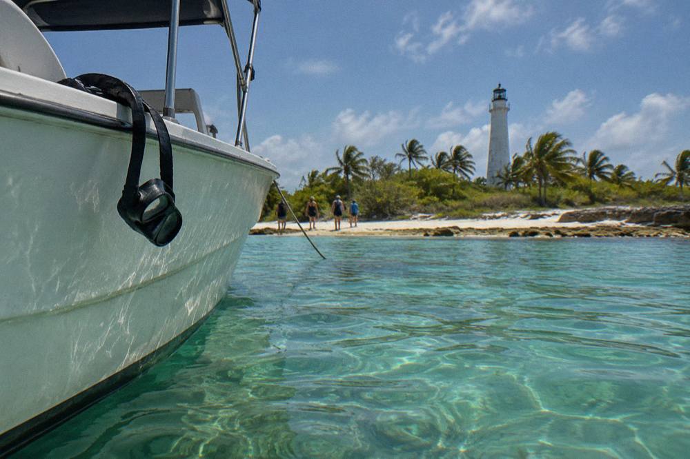 A anchored tour boat beside a shallow coral reef in clear turquoise water