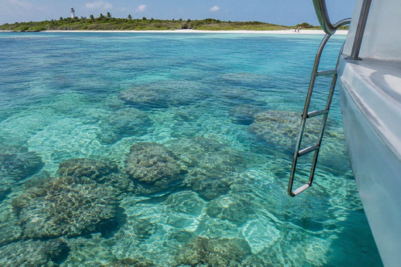 Calm turquoise water over a shallow coral reef with a boat anchored nearby