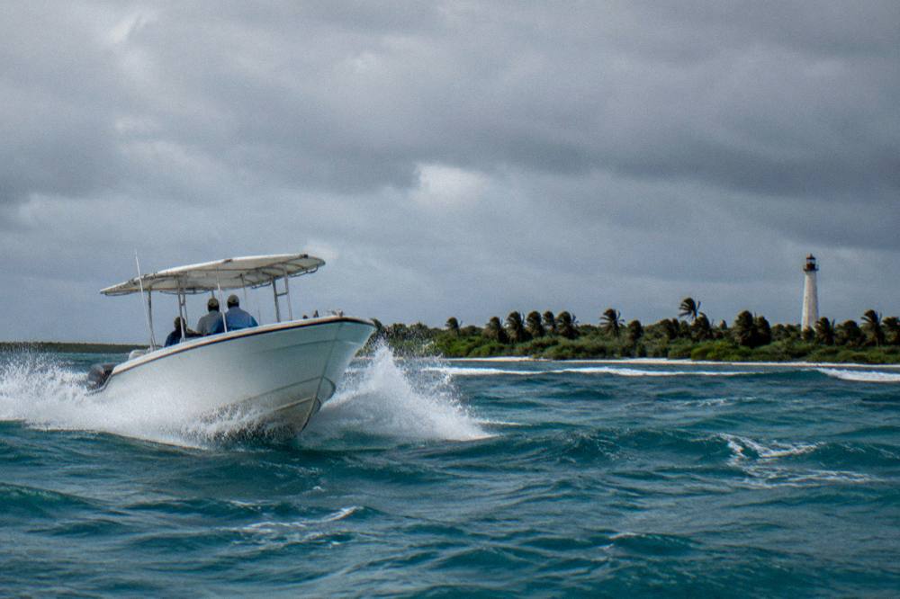 White speedboat cutting through choppy blue water with whitecaps under a cloudy sky