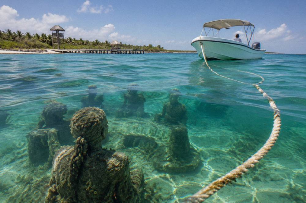 A speedboat anchored beside a coral reef with passengers in the water